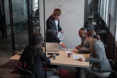 Image of a team working at a table with a smart board in the background