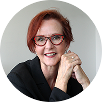 Dame rousse, porte des lunettes rouges, sourire aux lèvres